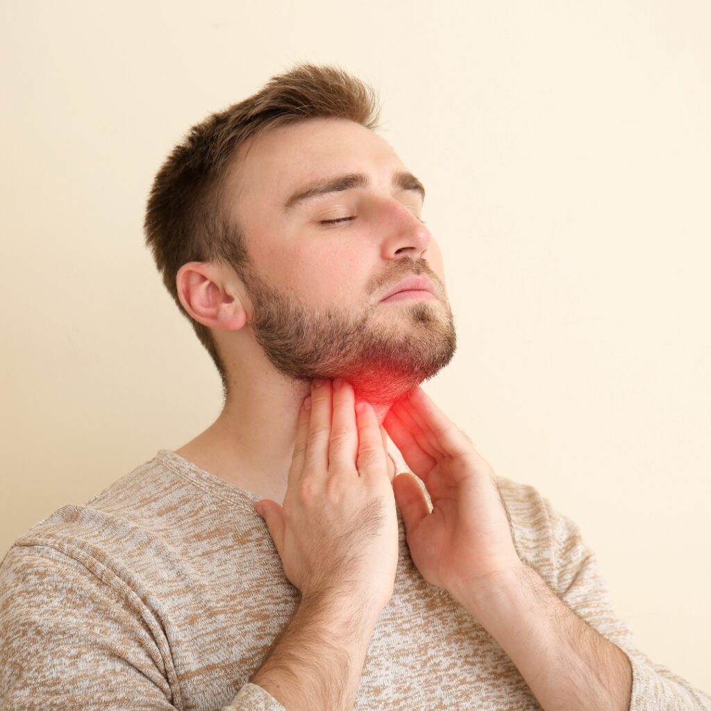 an holding his throat, indicating the thyroid area