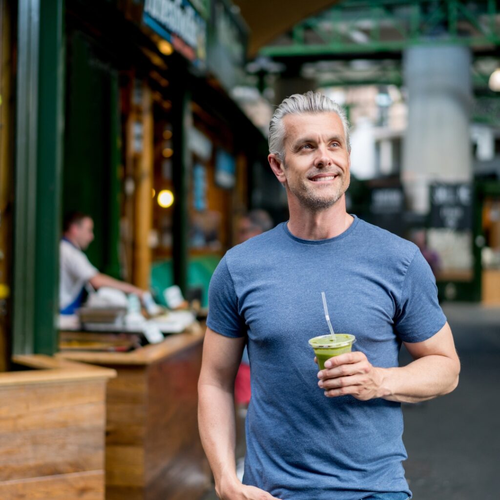 Energetic man walking outdoors with a green drink