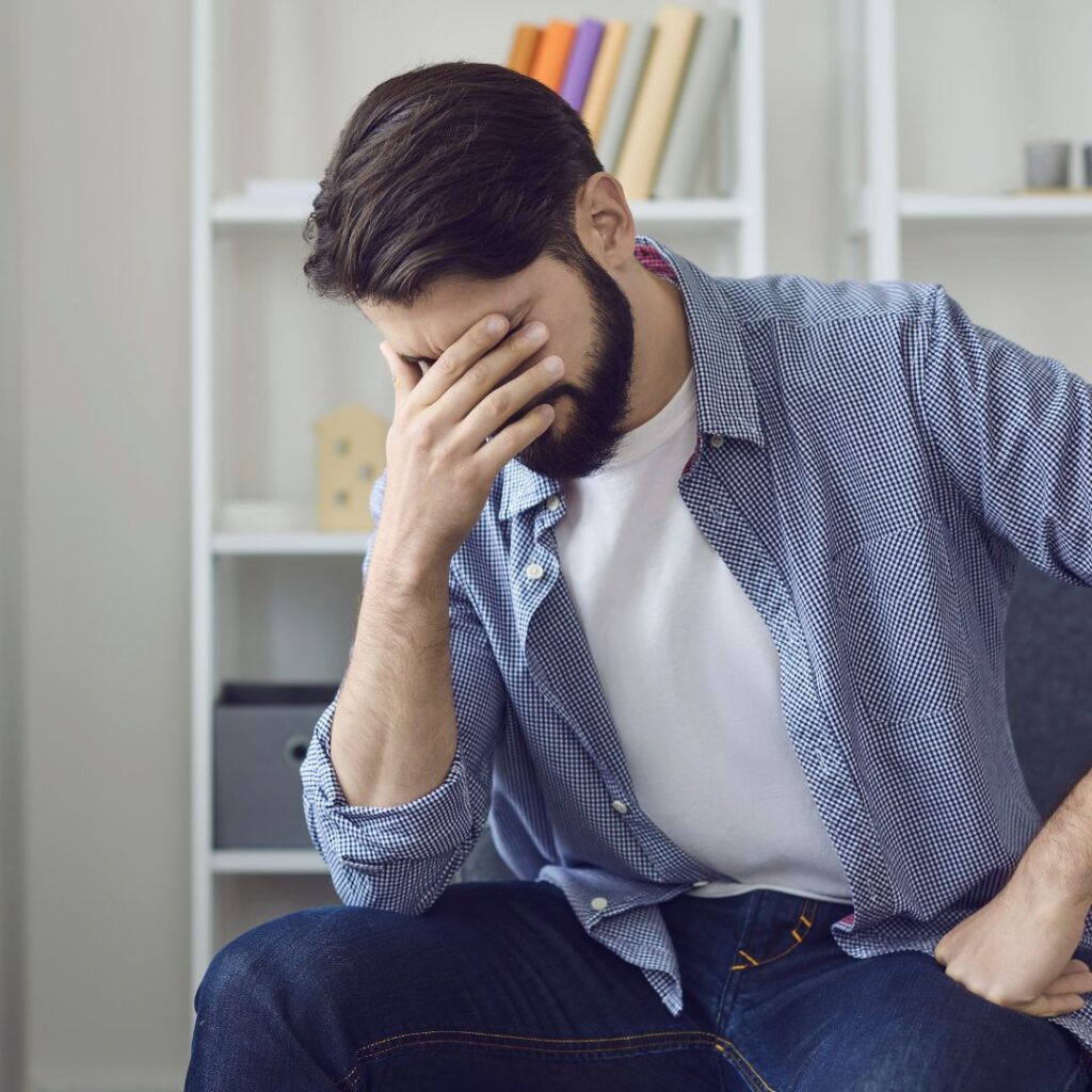 a man who is holding his head because he has a migraine