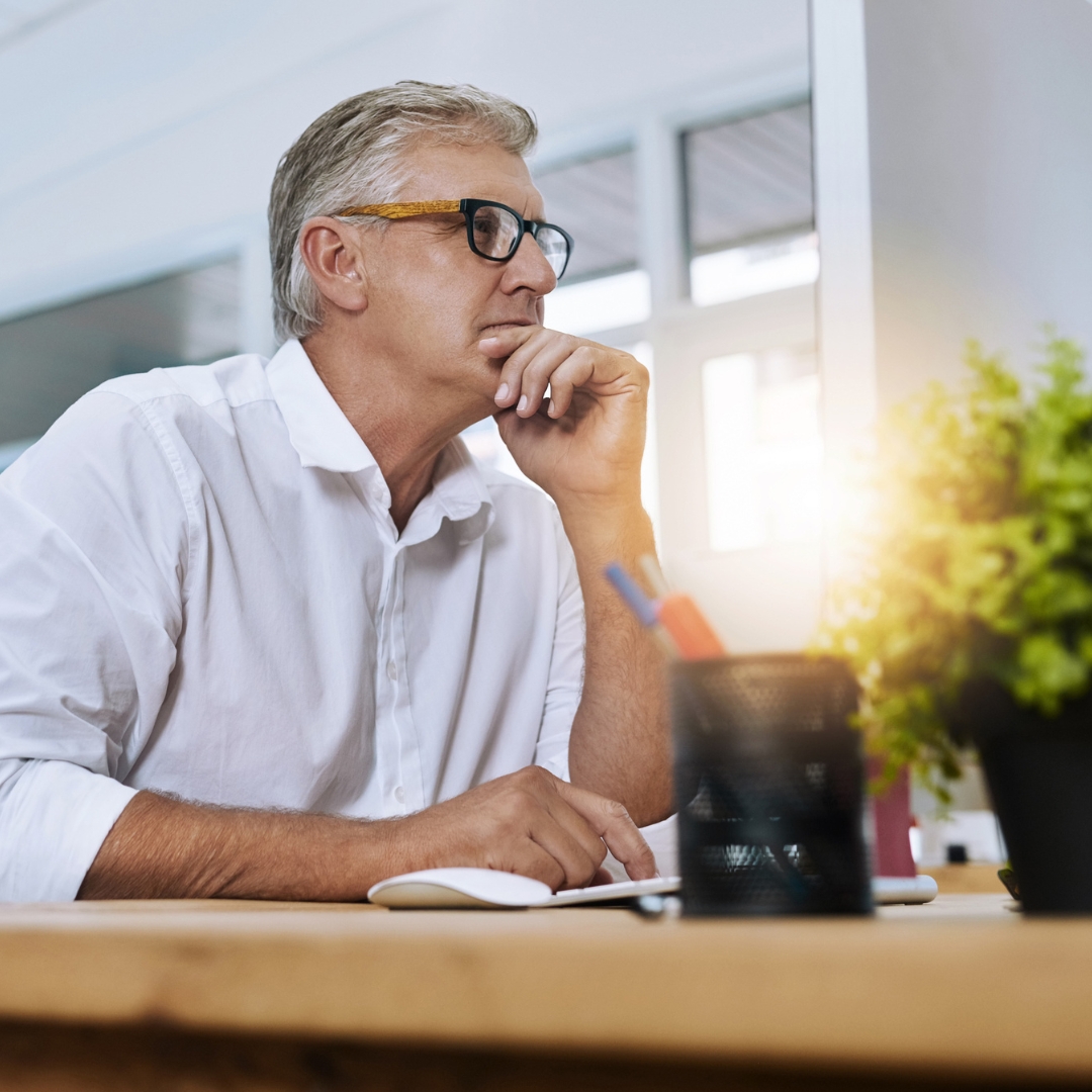 A man focused on work attentively using a laptop in a bright office.